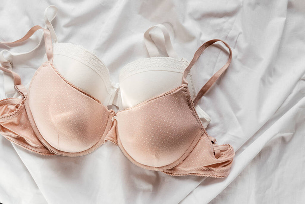 Valkoiset ja vaaleanpunaiset rintaliivit sängyllä. Naiset hellä alusvaatteet, alusvaatteet. Huippunäkymä, lähikuva. Tasainen lay, kauneus blogi tai sosiaalisen median minimaalinen käsite. Lahja ystävänpäivälahjaksi, Naisten päivä - Valokuva, kuva