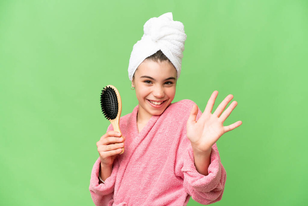 Jeune fille avec peigne à cheveux saluant avec la main avec expression heureuse - Photo, image