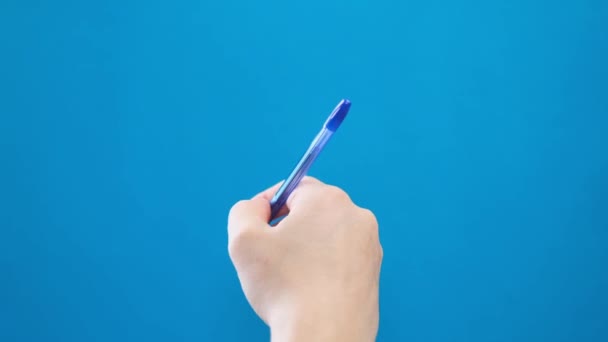 Male hand writing with a ballpoint pen in short strokes on a blue background. 4k video - Materiał filmowy, wideo