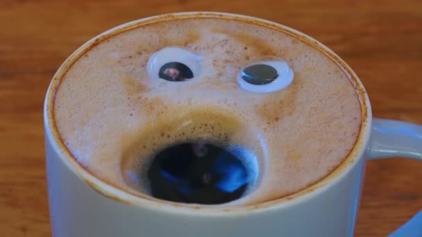 Close-up coffee cup with eyes and mouth screaming very loudly. Emoji coffee. Cheerful mood of the barista who made coffee with a human face. High quality 4k footage - Video
