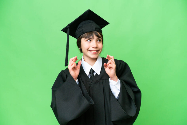 Маленькая университетская девочка на изолированном фоне со скрещиванием пальцев - Фото, изображение