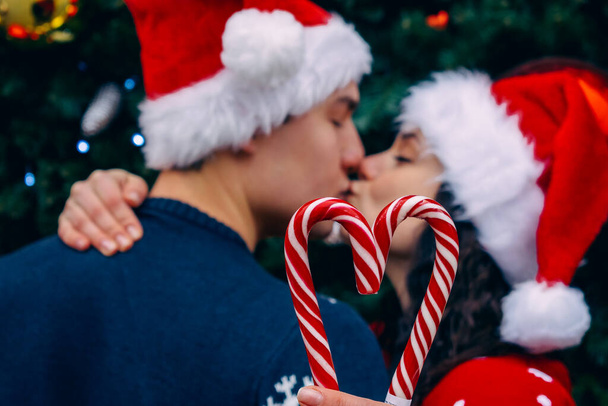 Christmas love. Man and woman in santa hats near the Christmas tree.  - Фото, изображение