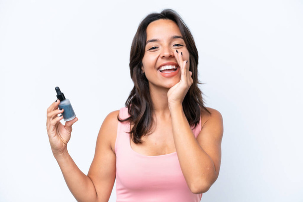 Young hispanic woman holding serum isolated on white background shouting with mouth wide open - Фото, зображення