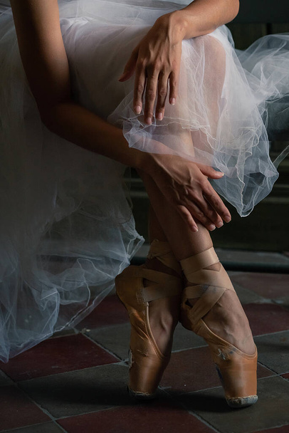 Primer plano de las piernas de una bailarina de pie en puntillas y las manos enderezando cintas en zapatos puntiagudos - Foto, imagen