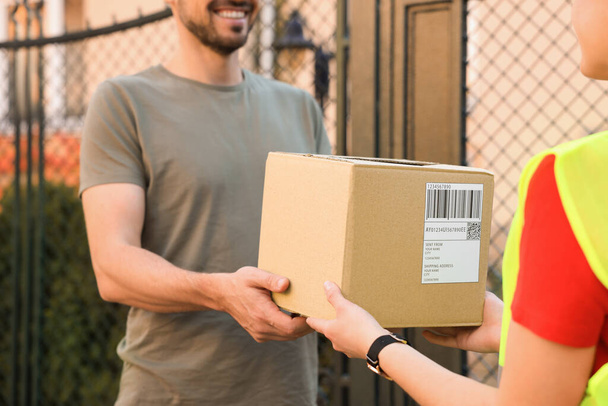 Man receiving parcel from courier outdoors, closeup - 写真・画像