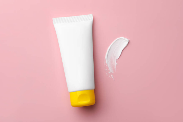 Tube of face cream and sample on pink background, top view - Foto, afbeelding