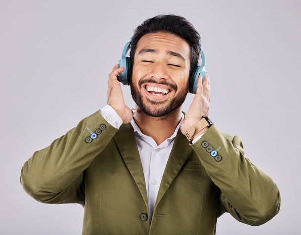 Music, headphones and business man singing in studio isolated on a gray background. Ceo, entrepreneur and smile of happy male singer streaming, listening and enjoying podcast, radio and song album - Photo, image