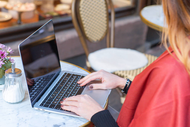 Egy fiatal üzletasszony ül egy kávézóban egy laptop mögött. Üzlet, online munka. Kiváló minőségű fénykép - Fotó, kép