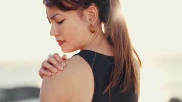 Hand, shoulder pain and beach with a runner woman outdoor for cardio or endurance exercise. Fitness, injury and running with a young female athlete rubbing her joint during a workout in nature. - Video, Çekim