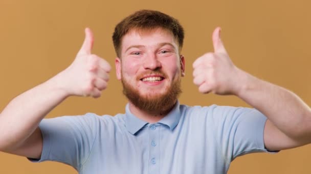 Redhead teenager shows his approval with a thumbs up in a studio shot, A young man gives a thumbs up and looks directly at the camera in a studio shot - Кадры, видео