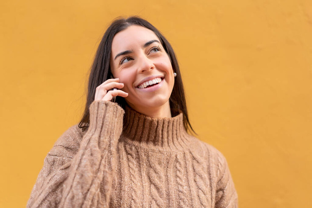 Jeune femme brune à l'extérieur gardant une conversation avec le téléphone portable avec quelqu'un - Photo, image