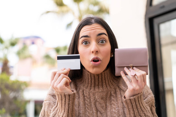 Young woman holding a credit card at outdoors - Valokuva, kuva