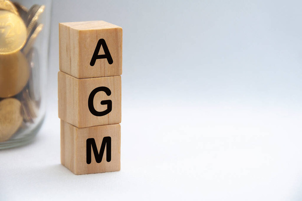 AGM text on wooden blocks with white cover background. Annual general meeting concept. - Photo, Image