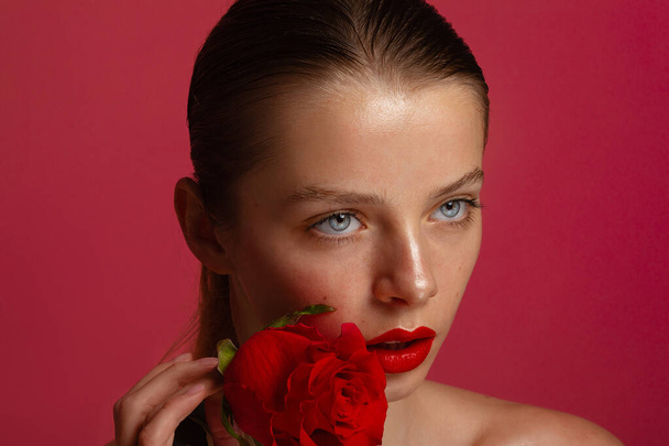 a beauty brunette woman portrait,a red rose flower in the hands, pink background, red lips - Fotografie, Obrázek