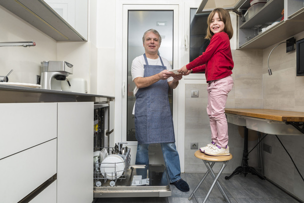 Семья опустошает посудомоечную машину
 - Фото, изображение