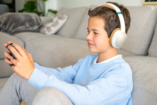Internet and social networks for teenagers, boy concentrated on phone, seats on sofa in living room - Photo, Image