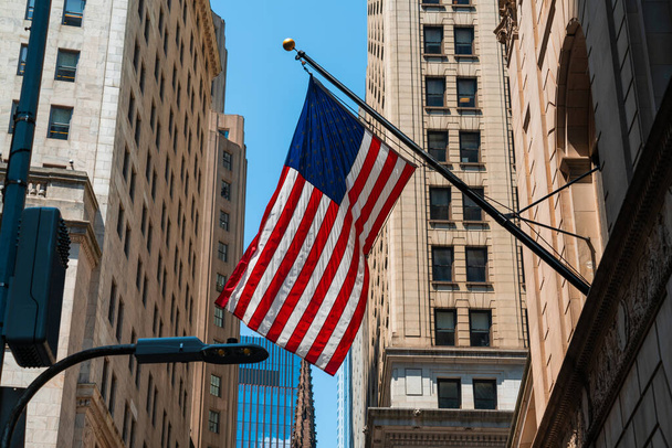 American flag against building in New York downtown, Manhattan. Wall street and US flag amongst different buildings - Foto, Imagen