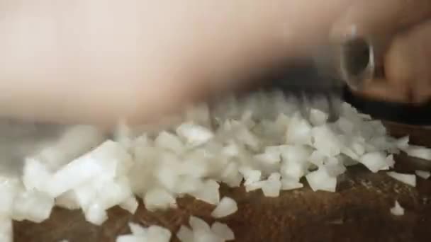 Kook snijdt uien met een mes op een houten plank. Video in slow motion. - Video