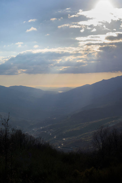 Vertical view of Valle del Jerte at sunset in winter with sun between clouds - Foto, Imagem