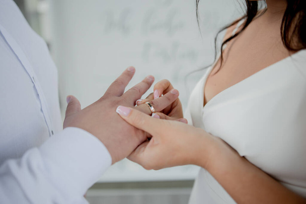 a bride and groom exchange wedding rings on their hands - Foto, Imagem