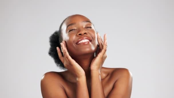 Beauty, portrait and black woman with a glow from skincare isolated on grey studio background. Cosmetic, smile and African girl touching her face for a soft, feminine and clear complexion and mockup. - Footage, Video