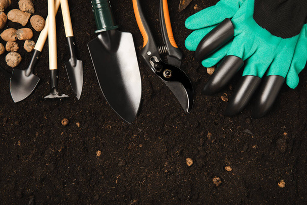 Garden tools and fertile soil. Garden rake, shovel, gloves, pruner and fertilizer. Gardening concept. Top view. Place to copy. Mocap. Banner. - Photo, Image