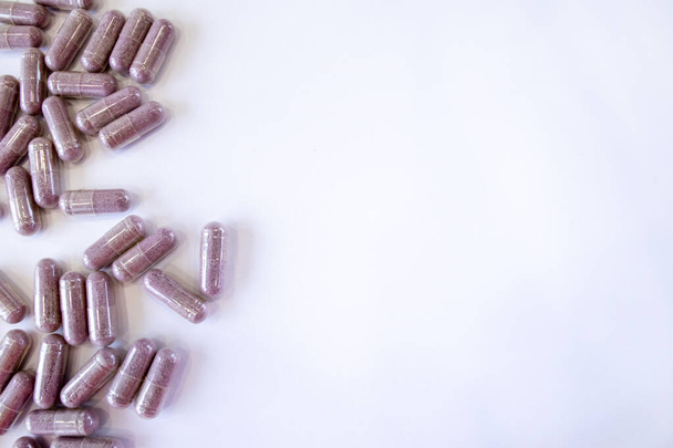 Pink capsules with additives on a white background. Tablets and medicines. Vitamins, minerals, plant extracts and other useful substances. Top view, copy space. - Foto, Imagem