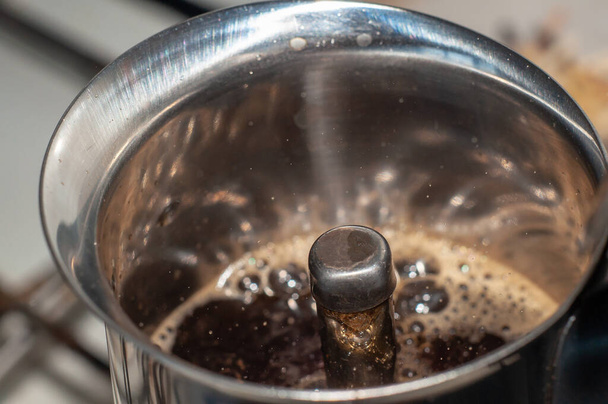 A frissen főzött kávét átöntik egy gejzír kávéfőző fúvókáján, és habot képeznek, egy nagy szöget a tetején.. - Fotó, kép