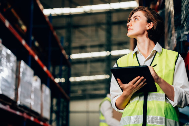 Warehouse supervisor using tablet for controlling and checking goods supplies on shelves with goods background in warehouse store, Logistic and business export concept - Φωτογραφία, εικόνα