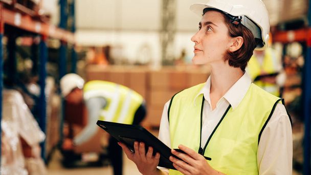 Happy warehouse engineer with safety vest using tablet for checking goods and supplies on shelves with goods background in warehouse store, Logistic and business export concept - Zdjęcie, obraz