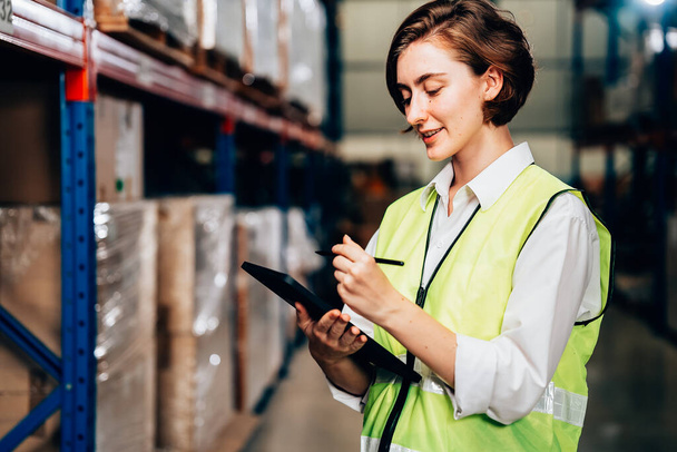 Warehouse supervisor using tablet for controlling and checking goods supplies on shelves with goods background in warehouse store, Logistic and business export concept - Photo, Image