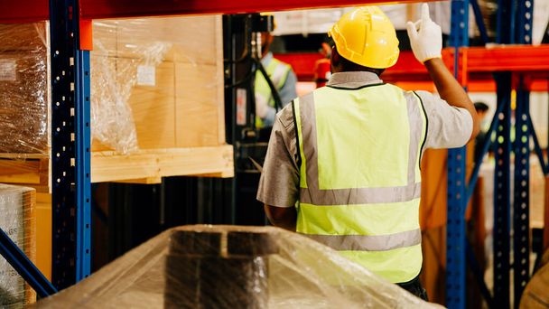 Warehouse workers with safety helmet checking and controlling boxes in warehouse, Professional warehouse workers moving cardboard boxes by forklift stacker loader, Logistic and business export concept - Photo, Image