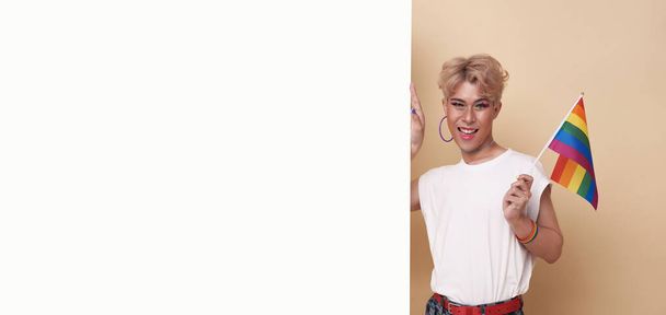 ЛГБТ-рука счастливого азиатского трансгендера демонстрирует чистый баннер объявления, выделенный на фоне студии. - Фото, изображение