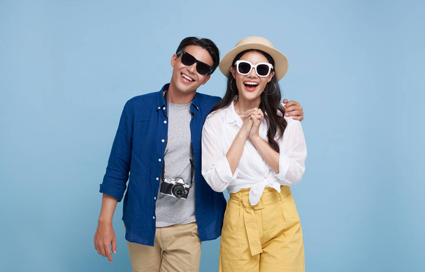 Захоплене подружжя азіатських туристів, одягнене в літній одяг, щоб подорожувати на свята ізольованих на синьому фоні. - Фото, зображення