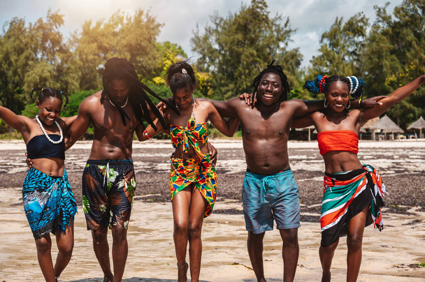 Des amis kenyans dansent sur la plage avec des vêtements locaux typiques - Photo, image