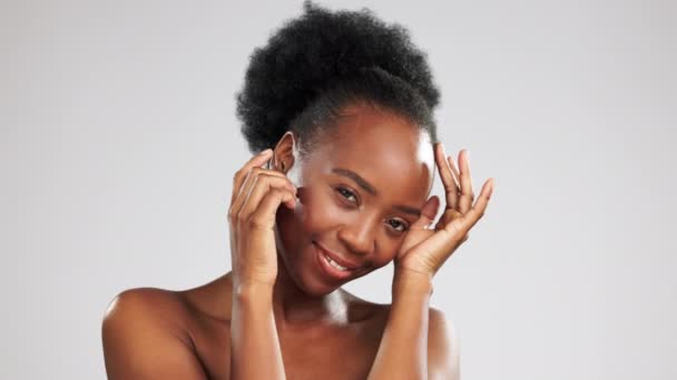 Huidverzorging, portret en zwarte vrouw raken gezicht geïsoleerd op een grijze studio achtergrond. Schoonheid, glimlach en Afrikaans meisje gevoel zacht, gloeiend en helder gezicht huid van dermatologie met mockup ruimte. - Video