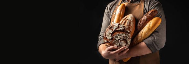 Άντρας που κρατάει τσιπς στα χέρια του. Διαφορετικοί τύποι ψωμιού. Προϊόντα αρτοποιίας σε σκούρο φόντο. Μορφή μεγάλου banner. - Φωτογραφία, εικόνα