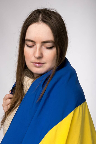 ein Mädchen europäischen Aussehens mit einer ukrainischen Flagge in Großaufnahme - Foto, Bild