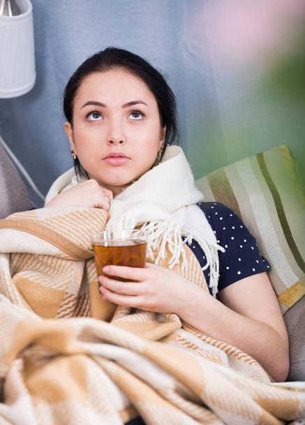 Ill girl drinking warm tea wrapping in blanket on couch - Zdjęcie, obraz