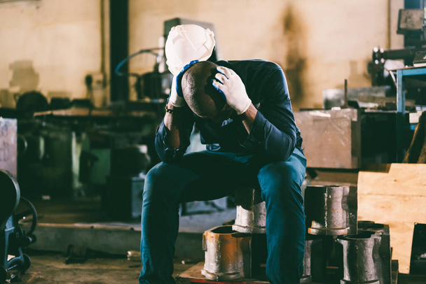 Boldogtalan és fáradt férfi ipari dolgozó fejfájással keményen dolgozó pozícióban - Fotó, kép