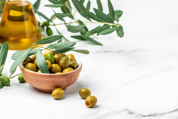 Branch with olives and a bottle of olive oil on white background. top view. place for text, - Photo, Image