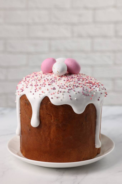 Tasty Easter cake with decorative sugar eggs on white marble table - Photo, image
