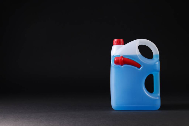 Plastic canister with blue liquid on black background. Space for text - Foto, afbeelding