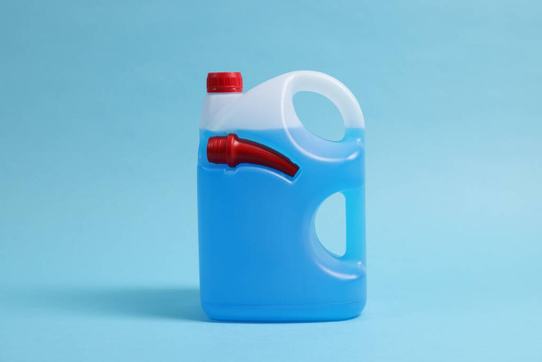 Plastic canister with color liquid on light blue background - Фото, зображення