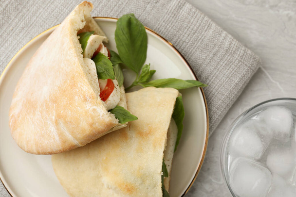 Delicious pita sandwiches with mozzarella, tomatoes and basil on light grey marble table, flat lay - Fotografie, Obrázek