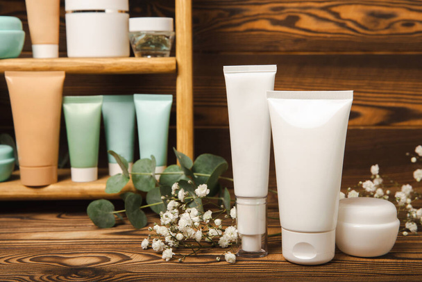 Skin care cosmetics on a brown wooden table. Cosmetic tubes in the bathroom. Cream, serum and face scrub. Facial care concept. MOCAP. - Photo, image