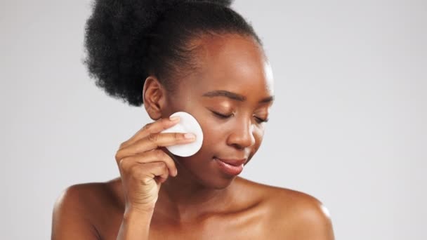 Πρόσωπο, περιποίηση δέρματος και μαύρη γυναίκα με βαμβάκι στο στούντιο απομονωμένη σε γκρι φόντο. Δερματολογία, μάτια κλειστά και γυναικείο μοντέλο με pad προσώπου για την αφαίρεση καλλυντικών μακιγιάζ για υγιές δέρμα και καθαρισμό - Πλάνα, βίντεο