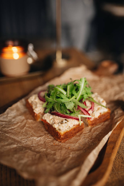 бутерброд с ветчиной, сыром и рукколой на деревянной доске - Фото, изображение
