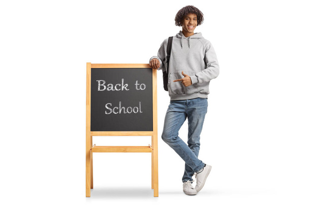 African american male student pointing at a blackboard with text back to school isolated on white background - Foto, immagini