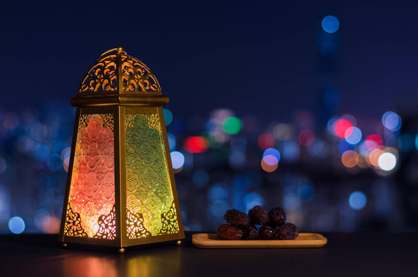 Lanterna e pequeno prato de frutas datas com céu noturno e cidade bokeh fundo de luz para a festa muçulmana do mês santo do Ramadã Kareem. - Foto, Imagem